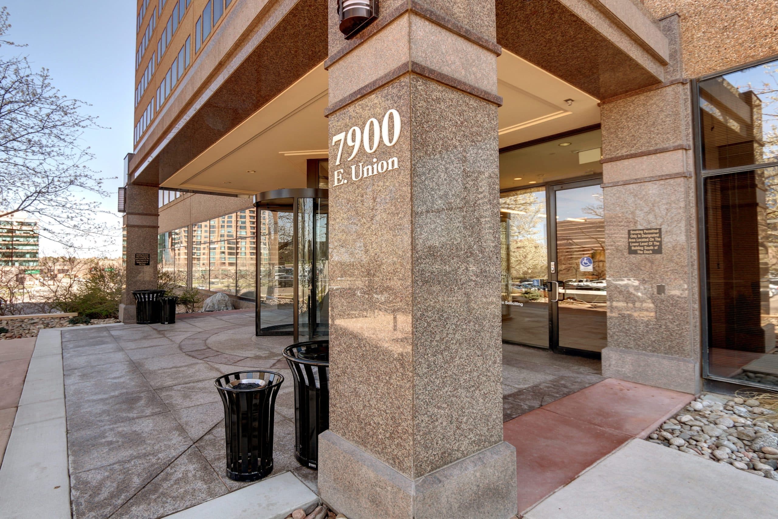 Modern office building entrance at 7900 East Union Avenue with glass doors and stone facade