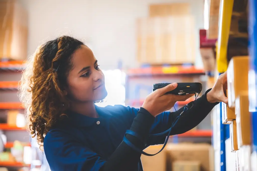 female worker using rugged barcode scanner to scan box in warehouse