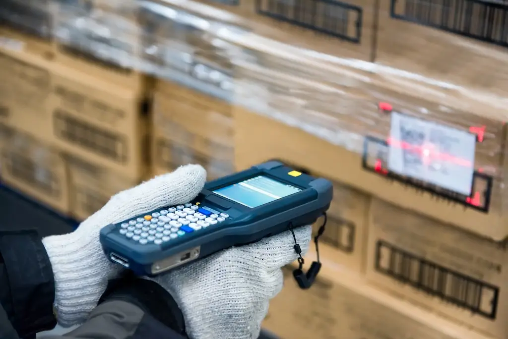 gloved hands using rugged mobile scanner in warehouse